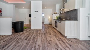 Eine moderne Küche mit weißen Schränken, einem schwarzen Mülleimer und Holzboden.