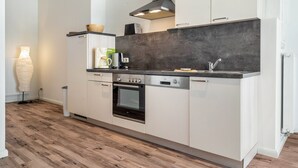 Eine moderne Küche mit weißen Schränken, einem eingebauten Backofen, einer Kaffeemaschine und einer Arbeitsplatte mit Spüle.
