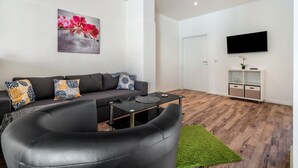 Ein modernes Wohnzimmer mit einer Couch, einem Couchtisch und einem flachbildfernseher an der Wand.