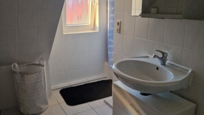 A bathroom with a window, a sink, a towel rack, and a trash bin. - Fantastic Apartment in the Heart of Wedel (Wedel)