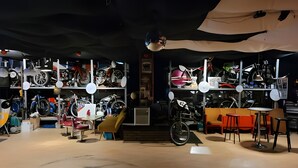 A room with bicycles on shelves, a staircase, and a table with chairs.