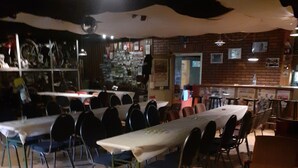 A restaurant with multiple tables and chairs, a brick wall, and a counter area.