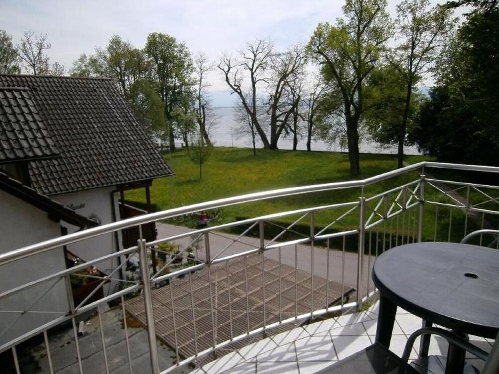 A balcony with a metal railing overlooking a grassy area and a body of water.