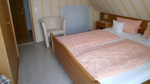 Une chambre à coucher avec un lit, une chaise, une table de chevet et une fenêtre avec des rideaux.