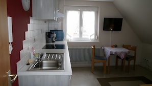 Une cuisine compacte équipée d’un évier, d’une cuisinière et d’un coin repas avec une table et des chaises.