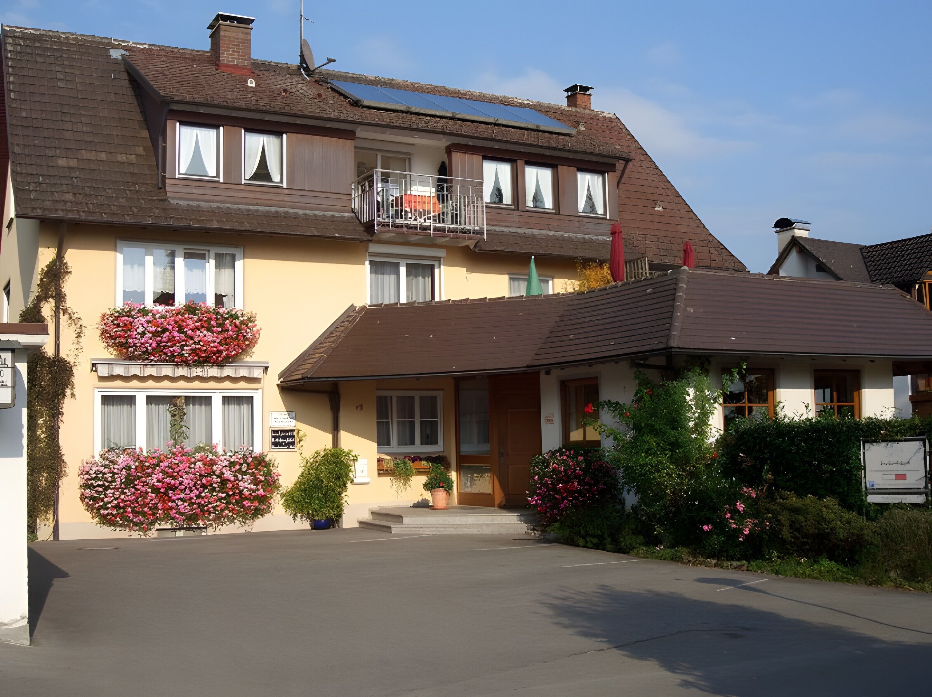 A two-story building with a balcony, flower boxes, and a sign indicating a restaurant.
