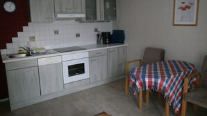 Une cuisine compacte équipée d’un évier, d’une cuisinière et d’un coin repas avec une table et des chaises.