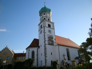A church with a clock tower, a red roof, and a green dome.
