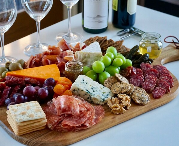Una tabla de embutidos con diversos quesos, carnes, frutas y nueces.