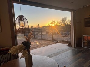 Una habitación con un amplio ventanal con vistas a un espacio exterior vallado al atardecer.