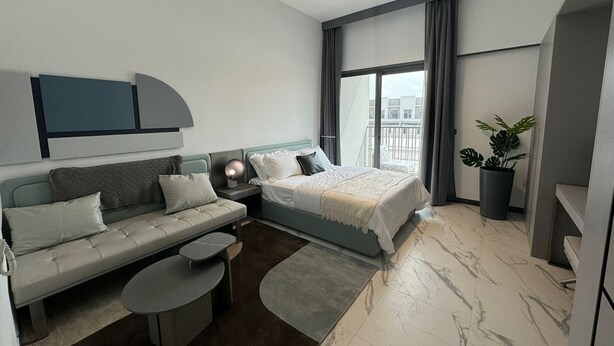 Une chambre d’hôtel moderne avec un lit, un canapé, une petite table et une plante en pot.