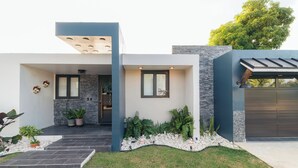 Een modern huis met een stenen gevel, een donkere garagepoort en een verzorgd gazon.