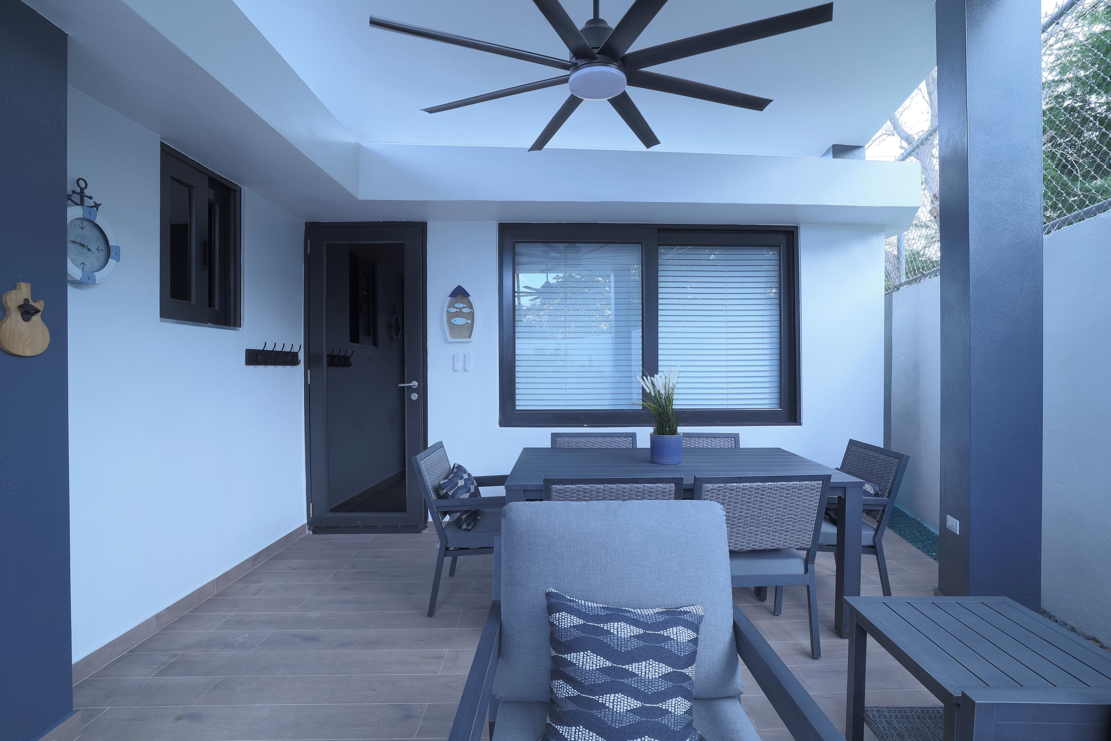 Une terrasse moderne avec un ventilateur de plafond, une table à manger avec des chaises et une plante en pot.