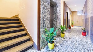 Een moderne hotel lobby met marmeren vloer, een trap en kamerplanten.