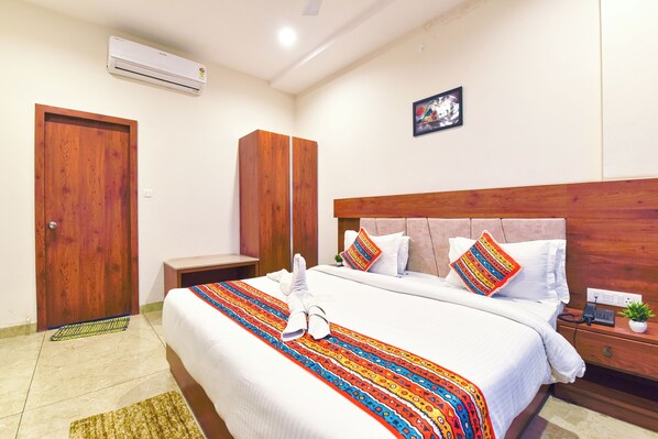 Une chambre d’hôtel comprenant un lit, une armoire en bois, une table de chevet avec un téléphone et un climatiseur fixé au mur.