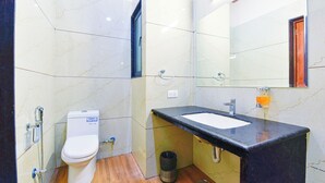 Een badkamer met toilet, wastafel, spiegel en betegelde wanden.