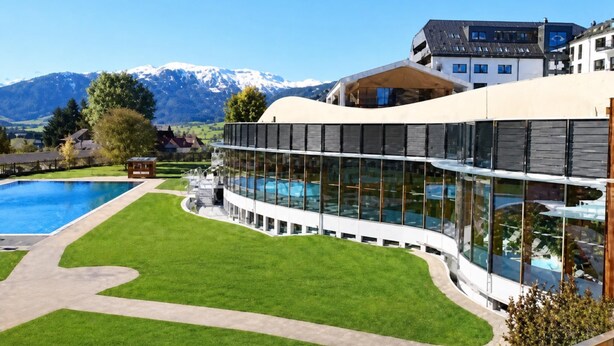 Un edificio moderno con piscina e vista sulle montagne innevate.