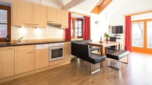 Una cucina moderna con mobili in legno, forno a incasso e zona pranzo con una panca e un tavolo.