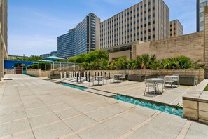 A rooftop terrace with a swimming pool, outdoor seating, and a view of surrounding high-rise buildings. - Modern Downtown Dallas City View High-Rise, Free Parking, Balcony, Pool, Gym (Dallas)