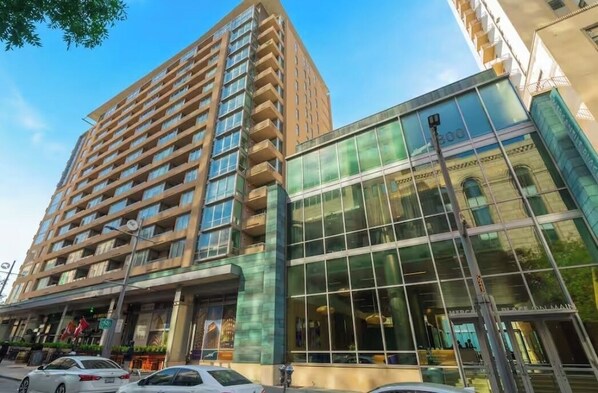 A high-rise building with a modern glass facade and a traditional brown exterior. - Modern Downtown Dallas City View High-Rise, Free Parking, Balcony, Pool, Gym (Dallas)