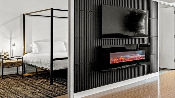 A modern bedroom with a four-poster bed, a flat-screen TV mounted on a black panel, and a fireplace. - Modern Downtown Dallas City View High-Rise, Free Parking, Balcony, Pool, Gym (Dallas)