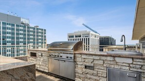 An outdoor kitchen with a stone countertop, a stainless steel grill, and a sink. - Modern Downtown Dallas City View High-Rise, Free Parking, Balcony, Pool, Gym (Dallas)