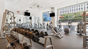 A gym with various exercise equipment, large windows, and a ceiling fan. - Modern Downtown Dallas City View High-Rise, Free Parking, Balcony, Pool, Gym (Dallas)