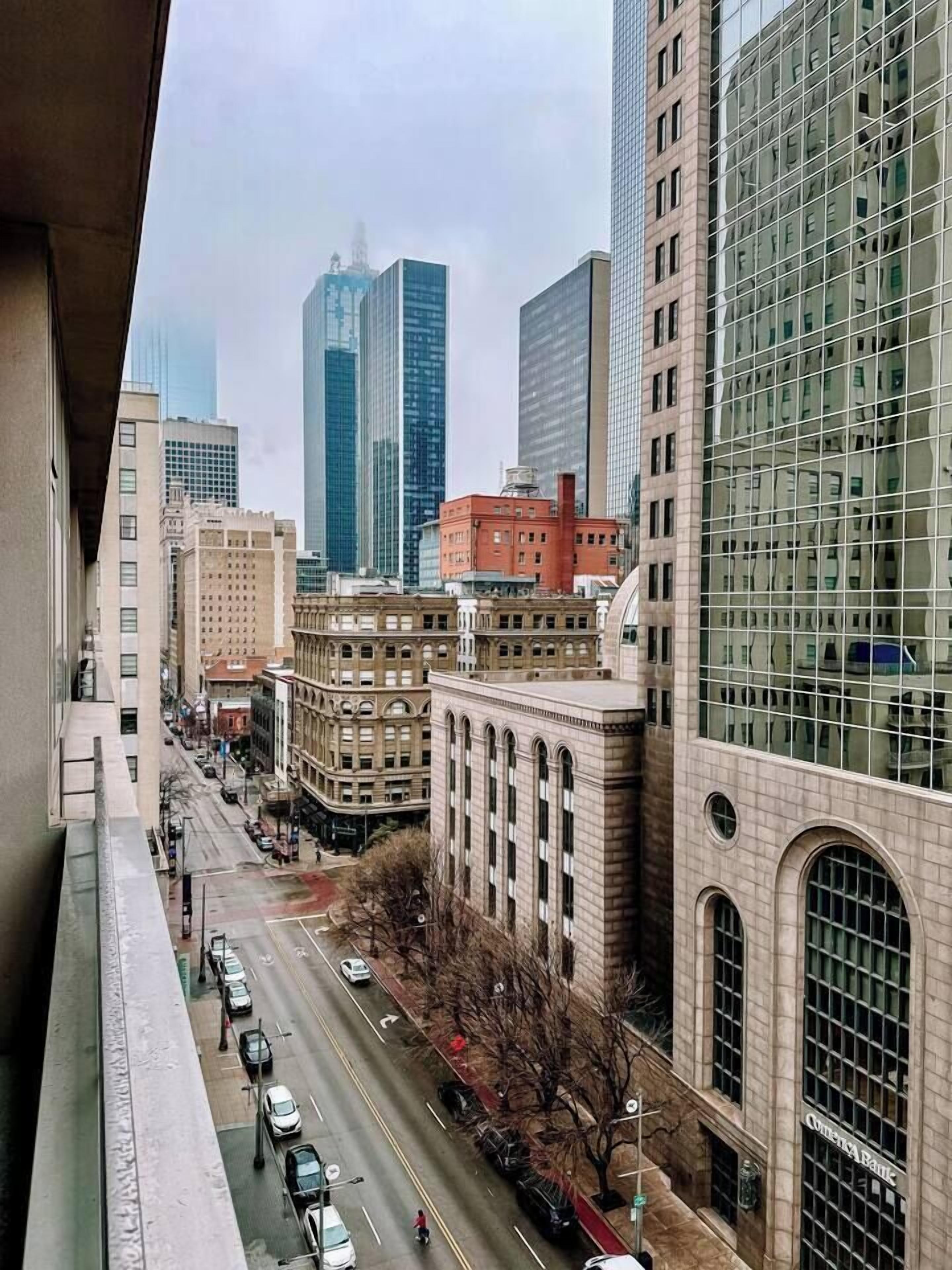 A city street with tall buildings, including a bank with a large glass facade.