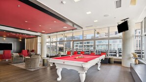 A pool table in a modern room with large windows, red accents, and comfortable seating. - Modern Downtown Dallas City View High-Rise, Free Parking, Balcony, Pool, Gym (Dallas)