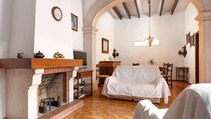 Una habitació acollidora amb una llar de foc, un sofà, una taula de dinar i un penjallum.