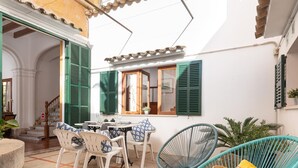 Zona de terrassa amb taula preparada per dinar, cadires de vimetla i una cadira de vimetla amb una revista.