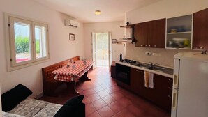 A compact kitchen with a dining table, a stove, and a refrigerator. - Casa Solana al Cavo meters from the sea (Cavo)