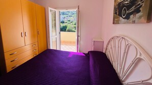 A bedroom with a bed, a wardrobe, a painting, and a balcony with a view. - Casa Solana al Cavo meters from the sea (Cavo)