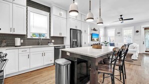 Una cocina moderna con armarios blancos, un refrigerador de acero inoxidable y una isla grande con taburetes de bar.