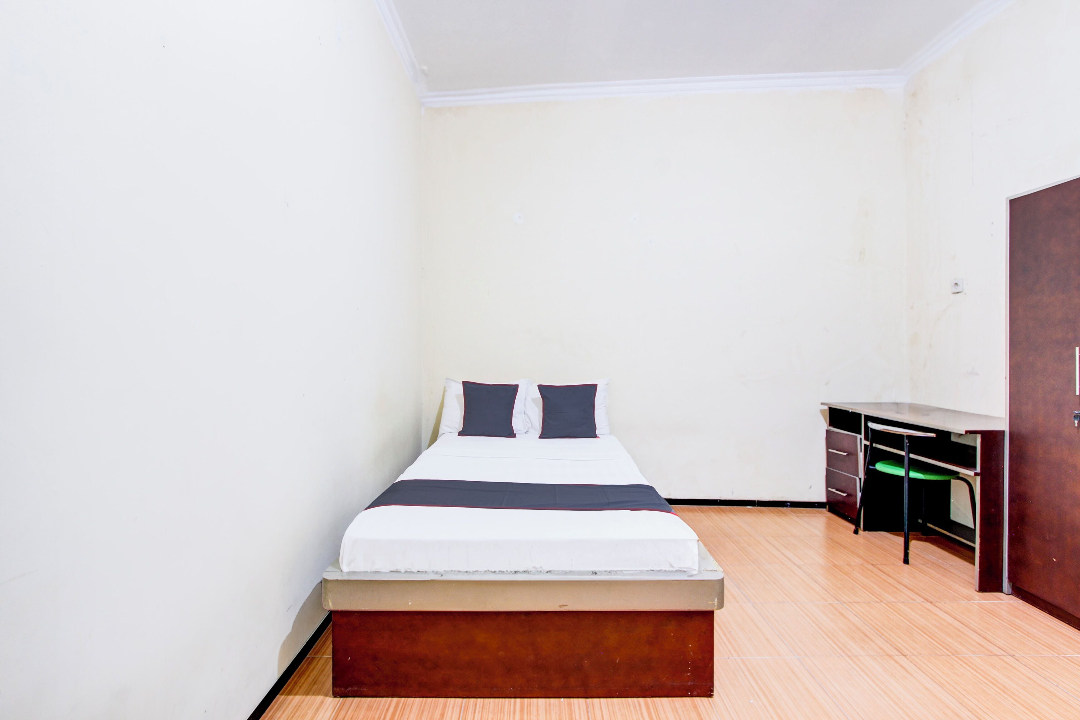 A small, clean room with a single bed, a desk, and a wardrobe.