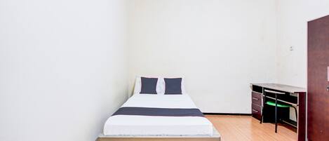 A small, clean room with a single bed, a desk, and a wardrobe.