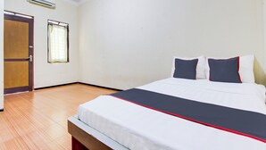 Een hotelkamer met een bed, een houten vloer, een deur en een raam.