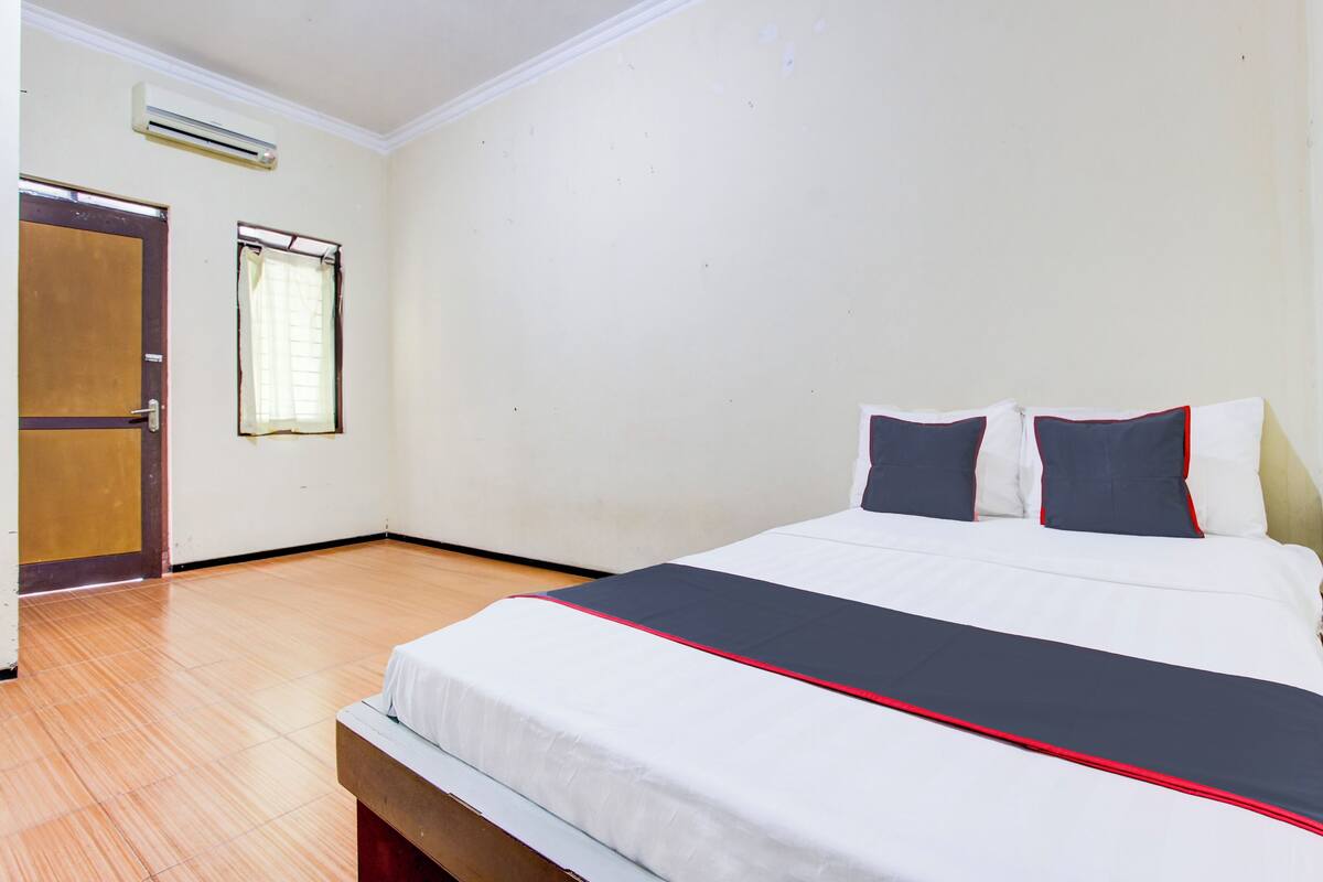 Une chambre d’hôtel avec un lit, un plancher en bois, une porte et une fenêtre.