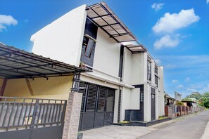 Una casa moderna de dos plantas con techo plano, ventanas amplias y entrada con portón.