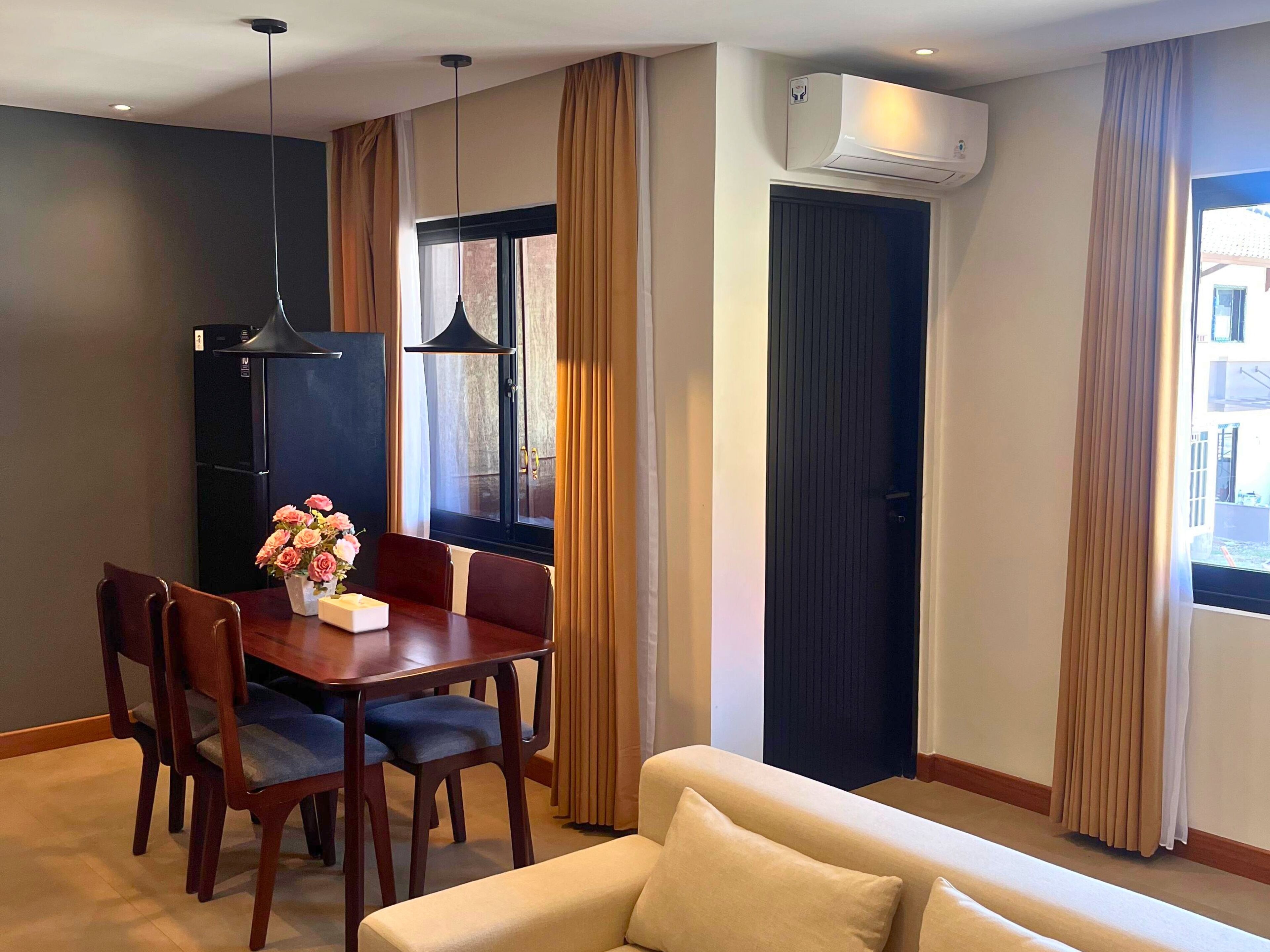 Un salon moderne avec un coin repas, comprenant un canapé, une table à manger, des chaises et un réfrigérateur.