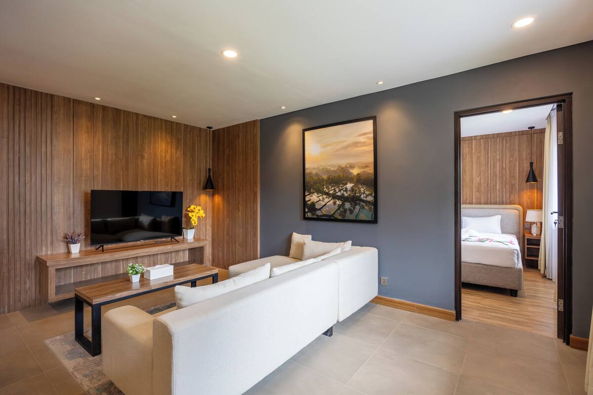 Un salon moderne avec un téléviseur à écran plat, un canapé, une table basse et un tableau accroché au mur.