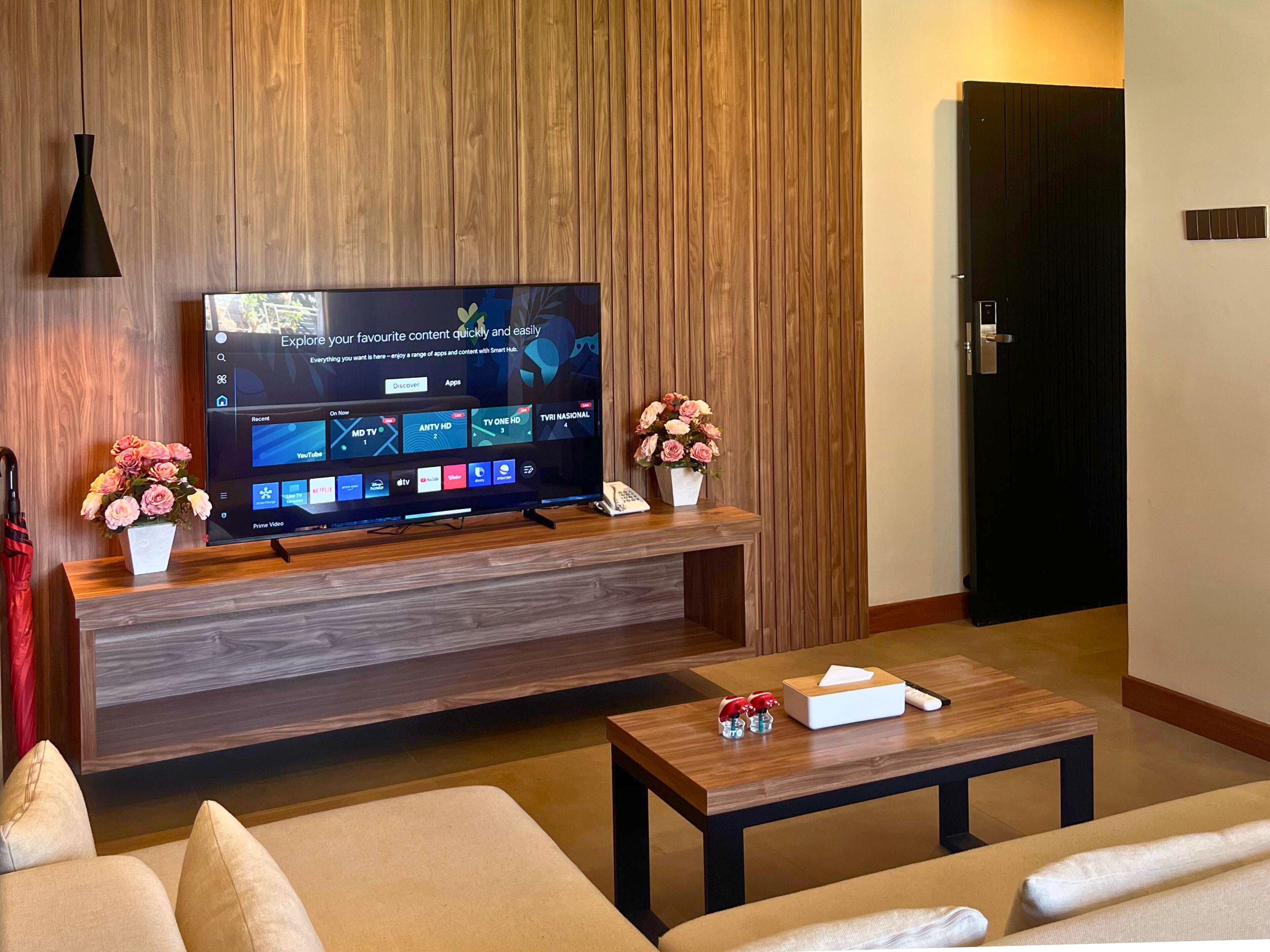 Ett modernt vardagsrum med en platt-TV placerad på en träkonsol, ett soffbord och en soffa.