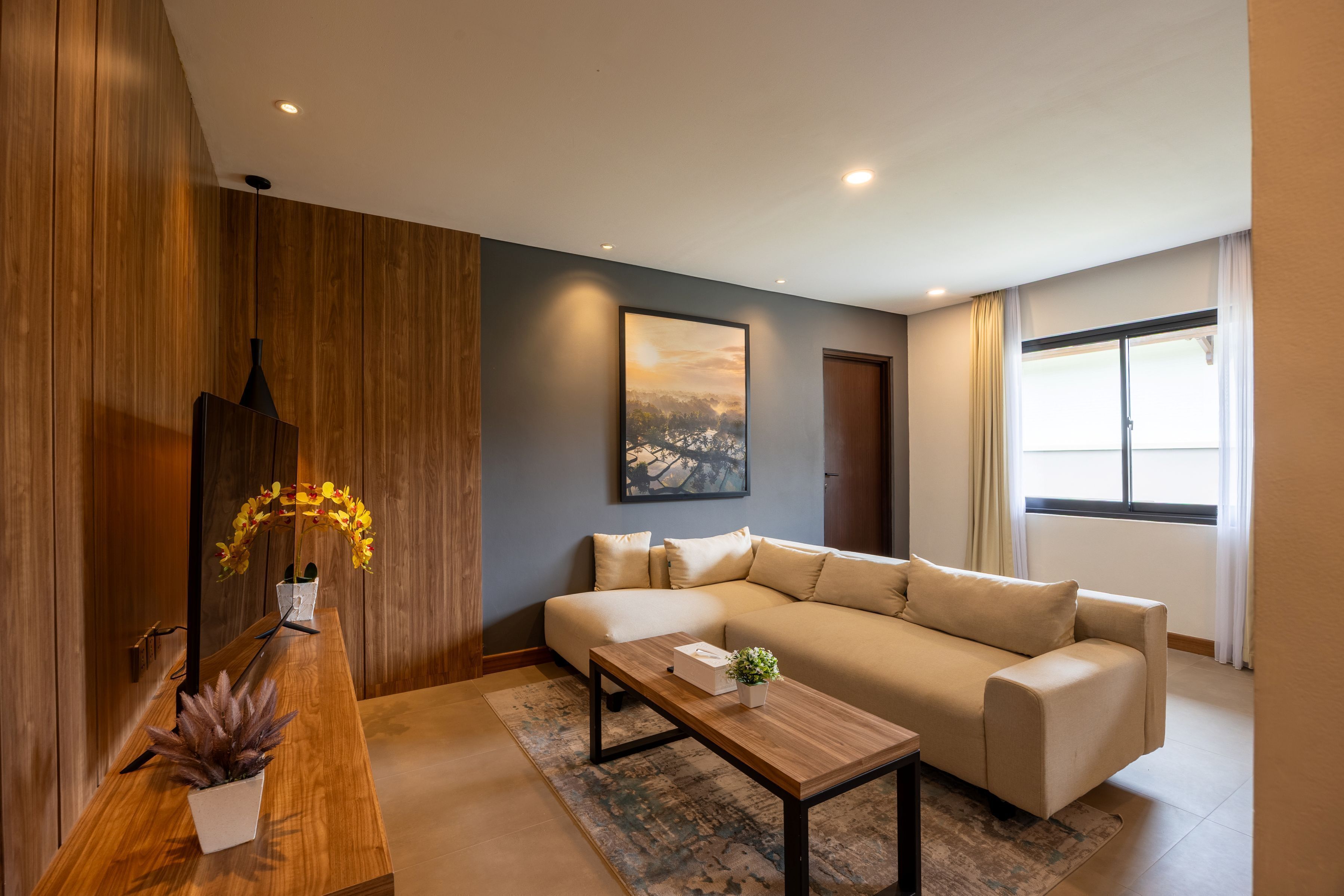 Una sala de estar moderna con un sofá color beige, una mesa de centro de madera y una planta en maceta.