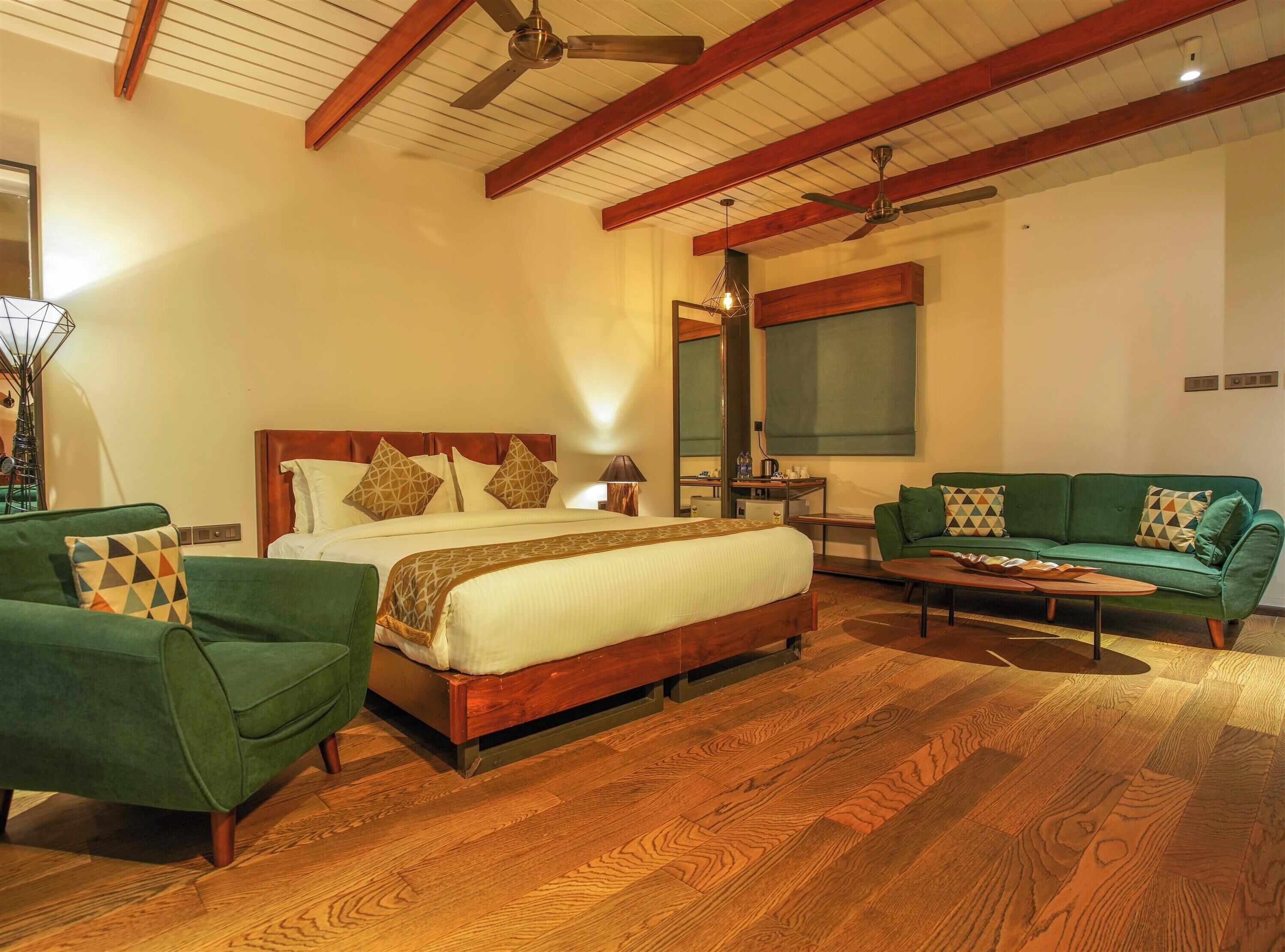 A spacious bedroom with a large bed, a green sofa, and a wooden floor.