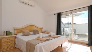 Una camera da letto con un letto, comodini, un tavolino di fianco al letto e una finestra vista, oltre a una ventola a soffitto.