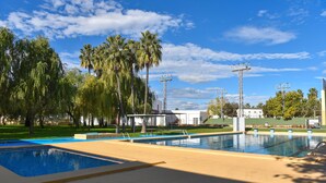 Una piscina divisa in due sezioni, circondata da palme e un cielo azzurro intenso.