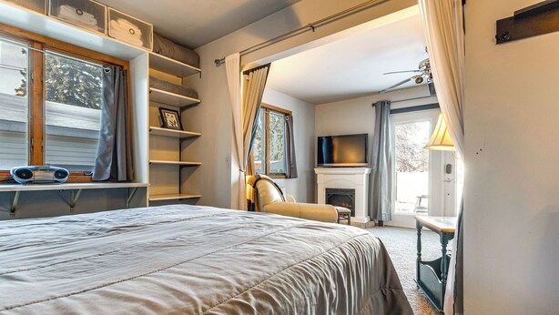 Ein Schlafzimmer mit einem großen Bett, einem Kamin, einem Fernseher und einem Fenster mit Vorhängen.
