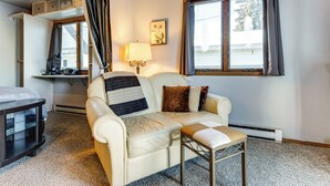 Ein gemütliches Zimmer mit einer Couch, einem kleinen Tisch, einer Lampe und einem Fenster.
