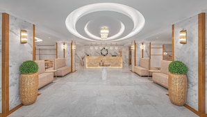 Um hall amplo com piso de mármore, um balcão de recepção central e luminárias modernas.