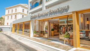 Um hotel boutique com fachada moderna, amplas janelas e uma entrada convidativa com plantas em vasos.